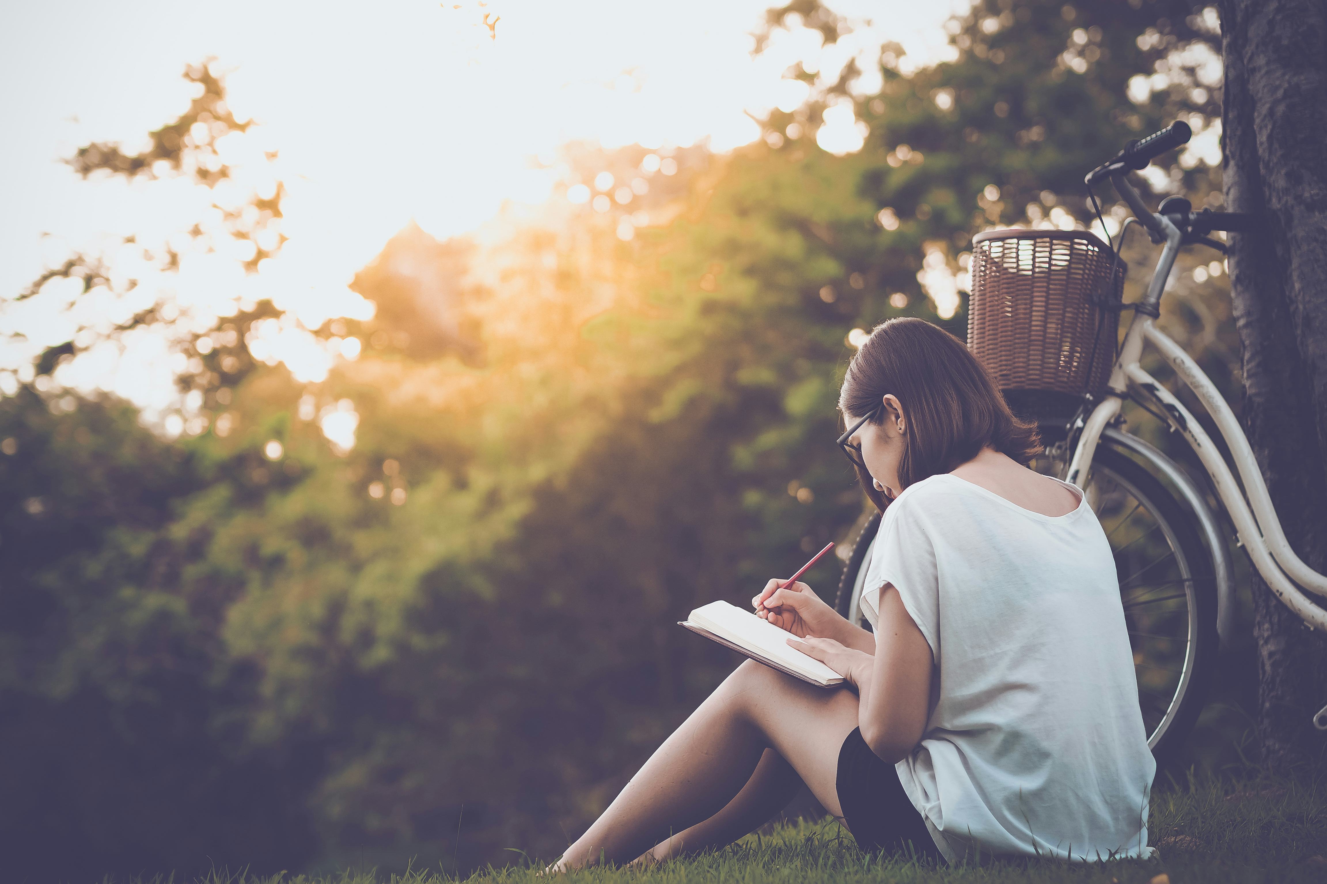 beautiful woman writing into her diary, in the park