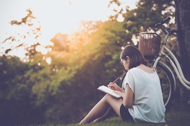 beautiful woman writing into her diary, in the park