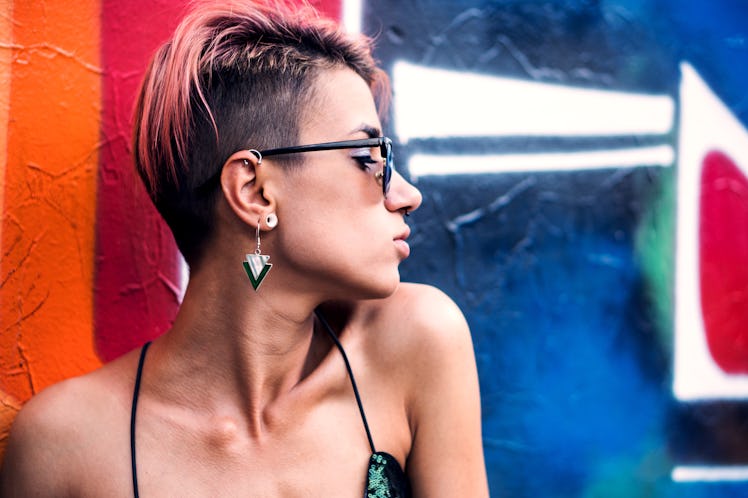 Street punk or stylish girl with pink dyed hair. Woman with piercing in nose, ears tunnels and unusu...