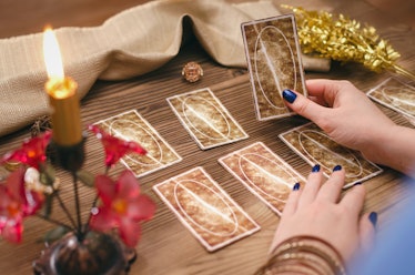 Tarot cards and hands of fortune teller on wooden table background.