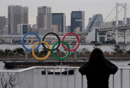 A pedestrian watches the Olympic Rings monument on a vessel being installed at Odaiba, Tokyo, Japan,...