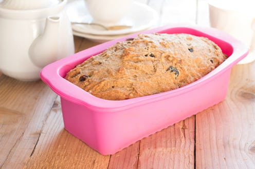 Sweet whole-wheat bread with bananas, nuts and raisins in silicone bakeware on wooden background