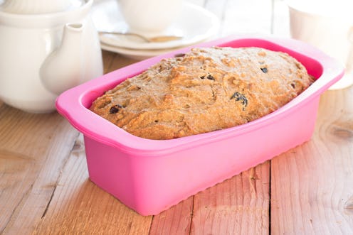Sweet whole-wheat bread with bananas, nuts and raisins in silicone bakeware on wooden background