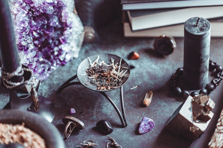 Smoked herbs on a witch's altar for a magical ritual among crystals and black candles.
