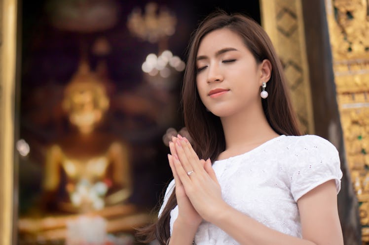 Religious Asian buddhist woman praying. Female buddhist disciple meditating, chanting mantra with pr...