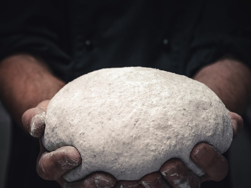 a men holds a dough for bun roll and for baking. Fresh bread yeast