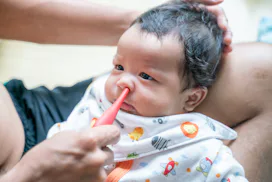 Father suctioning baby boy's nose with bulb syringe