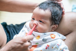 Father suctioning baby boy's nose with bulb syringe