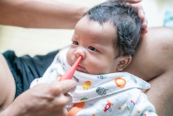 Father suctioning baby boy's nose with bulb syringe