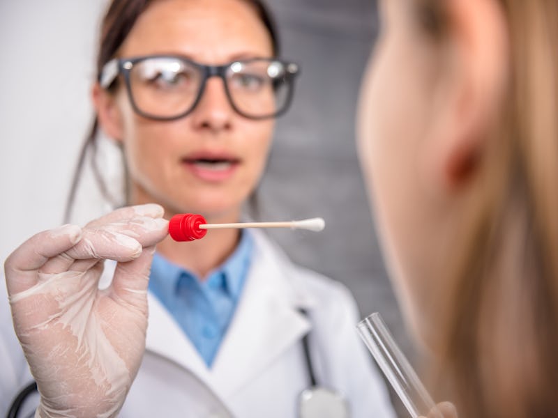 Female pediatrician using a swab to take a sample from a patient's throat