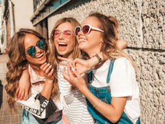 A trio of women laughing think of group chat names for 3 best friends.