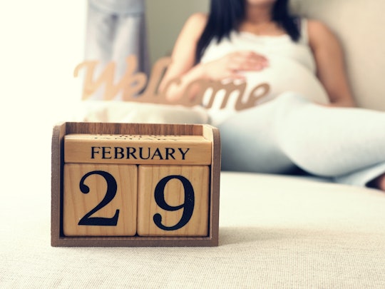 Baby's due date calendar on leap day with pregnant woman background. Maternity concept. Expecting an...