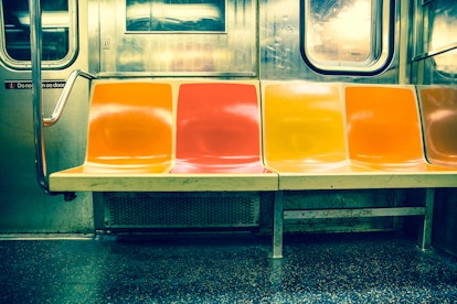 View inside New York City subway train car with vintage orange, yellow and red color seats