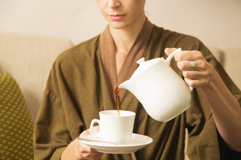Woman pouring coffee from the kettle into the cup