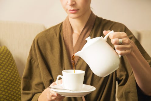 Woman pouring coffee from the kettle into the cup	