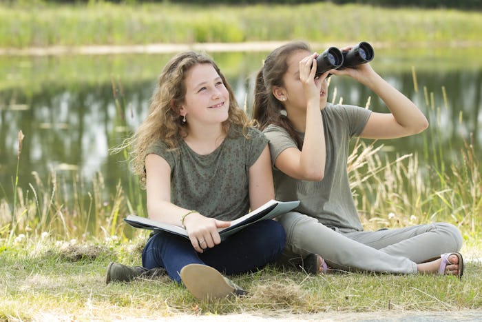 young girls exploring the environment with a binocular 