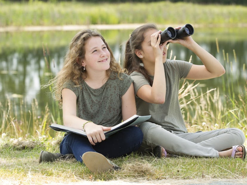 young girls exploring the environment with a binocular 