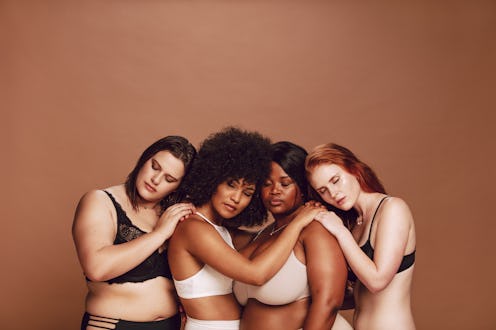 Multiracial group women in lingerie hugging each other with their eyes closed. Women of different we...