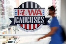 A pedestrian walks past a sign for the Iowa Caucuses on a downtown skywalk, in Des Moines, Iowa