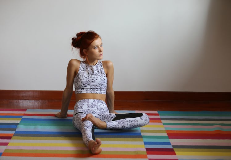 A young woman sits on a colorful yoga mat in a studio in New York City.