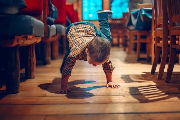 Cute adorable boy three years old having fun in cafe restaurant. Child playing on floor in public pl...