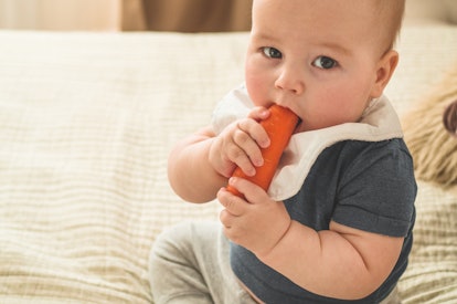 a baby boy gnawing on a carrot