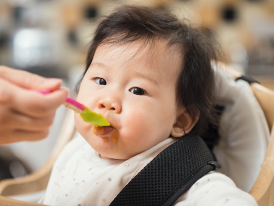 baby in high chair eating food from spoon
