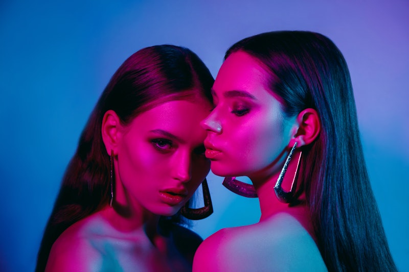 High fashion models in colorful bright neon lights posing at studio. Portrait of beautiful girls wit...