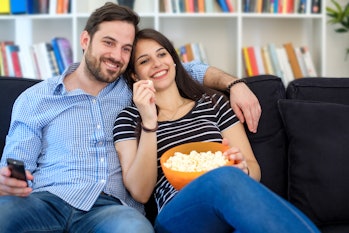 Young couple watching tv at home and having fun