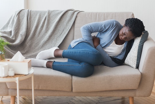 Menstrual Pain. Sick Young Black Woman Lying On Couch At Home Suffering From Abdominal Ache