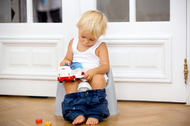 Infant child baby boy toddler sitting on potty, playing with toys in living room, indoors
