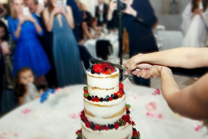 Look from behind on the wedding couple cutting beautiful cake
