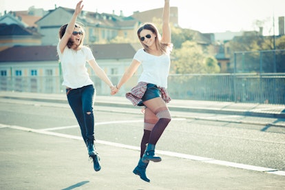 two beautiful young women jumping and dancing in the city