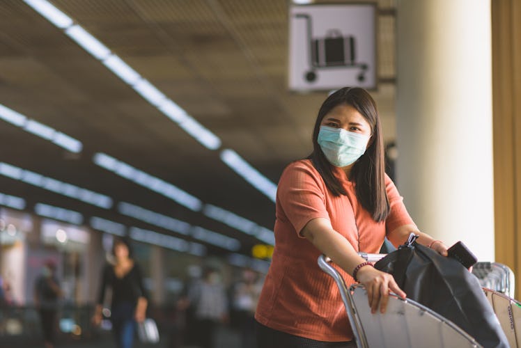 Asian women are traveling to travel within the country. At the airport building She wears a mask to ...