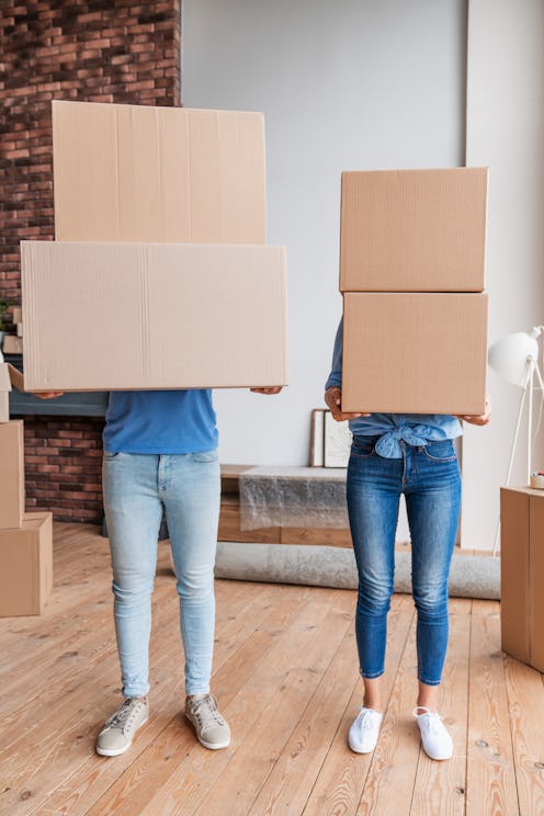 Unrecognizible playful couple with boxes in hands