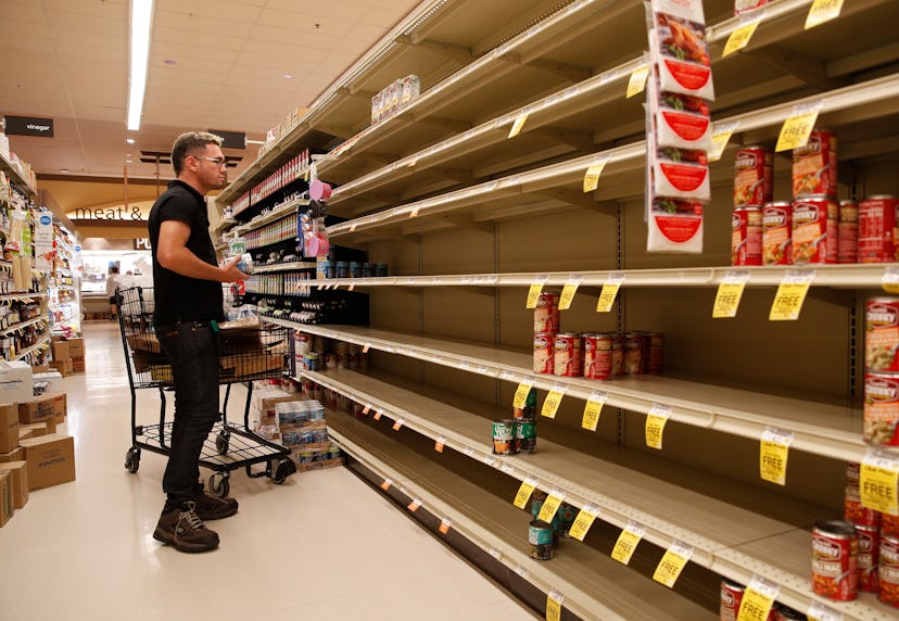 A worker looks at empty shelves for canned goods at a supermarket ahead of Hurricane Lane, in Honolu...