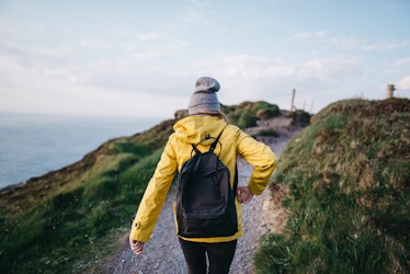 A female backpacker walks along the coast in Ireland.