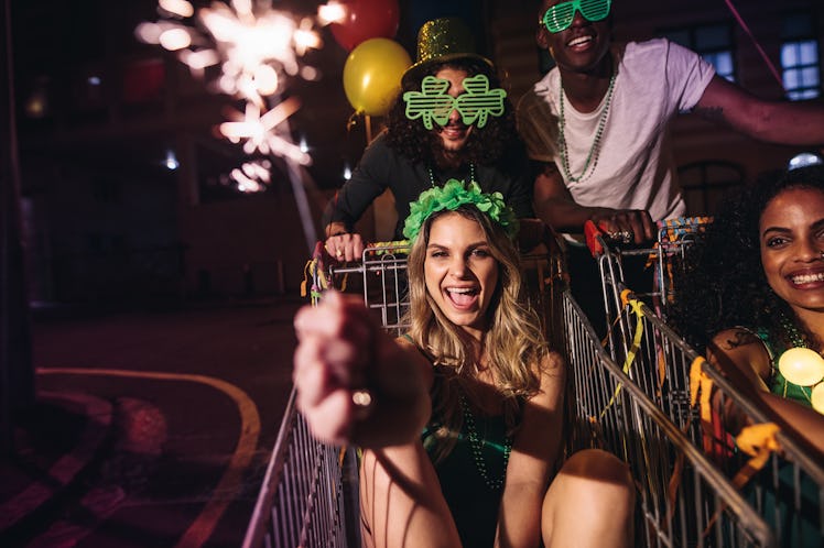 A group of friends celebrates St.Patrick's day with sparklers at night in the city.
