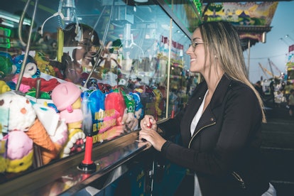A young woman plays on a claw machine.