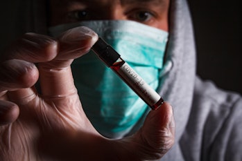 Doctor with respirator mask hold positive blood test of coronavirus