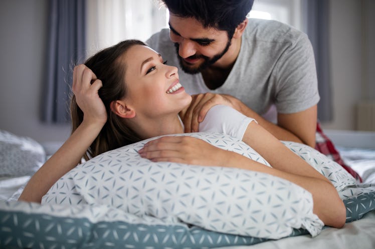 A smiling couple gives each other massages at home.