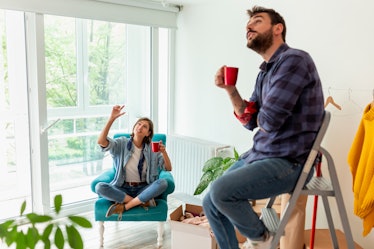 Couple moving in together, taking a break from unpacking the boxes, drinking coffee and planning arr...