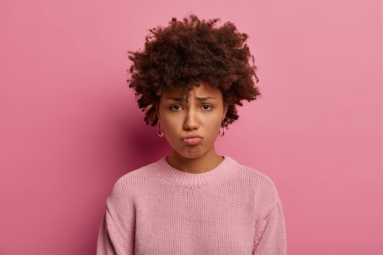 Headshot of sad gloomy woman pouts lips, looks with sorrowful expression at camera, feels hurt and d...