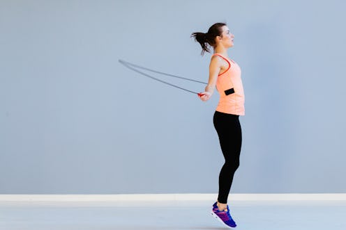 Beautiful sports girl doing exercises with jumping rope.