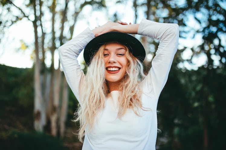 Happy girl in nature wearing a hat with black phone with green background white t-shirt