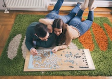 Top view of young couple laying on floor and doing puzzle