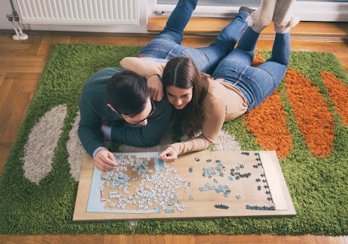 Top view of young couple laying on floor and doing puzzle