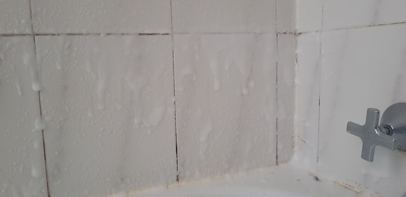 Mouldy Bathroom tiles covered with white foam spray cleaner