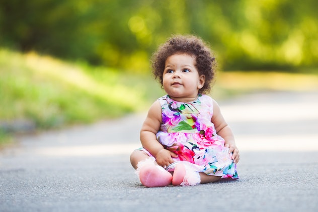 Cute and funny little girl wearing a colorful flowers dress, outdoors