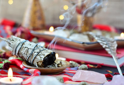 smudge stick with crystals candles and feathers on red sacred space
